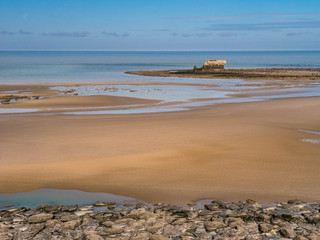 Fort on the waterline from Napoleon era with beach and rocks in the foreground