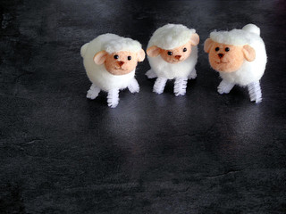 Three sheep figures on dark background