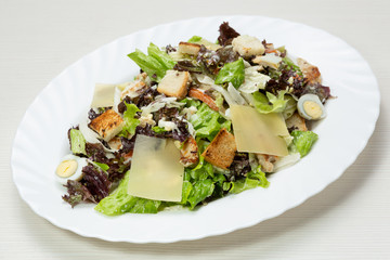 Caesar salad, with quail eggs, on a white oval plate