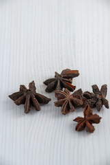 Vertical close-up of star anise on white wooden background with copy space