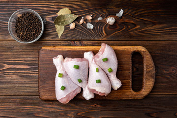 Raw chicken legs on dark wooden background.