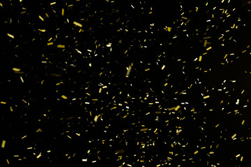 Thousands of confetti fired on air during a festival at night. Image ideal for backgrounds. Gold are the confetti in the picture. The sky as background is black. 
