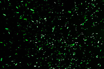 Thousands of confetti fired on air during a festival at night. Image ideal for backgrounds. Green are the confetti in the picture. The sky as background is black