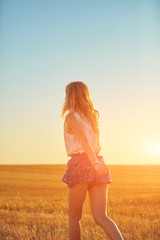 Obraz premium Cute young woman jumping in a wheat field.