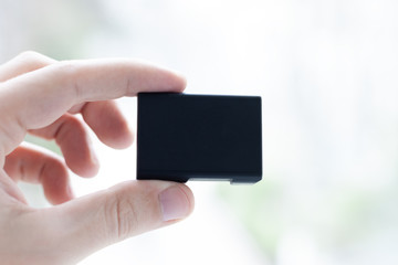 battery cell in hand at light abstract background.