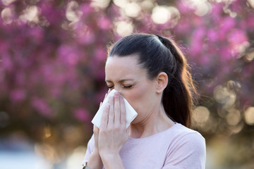 Woman blowing nose because of spring pollen allergy