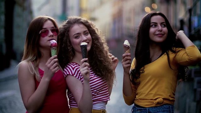 Young teenage female friends with ice cream standing outdoors in town.