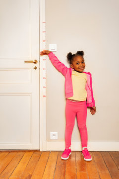 Little girl over scale on wall measure height