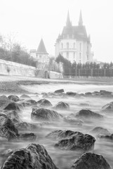 Retro style photo of seascape with stones and castle on the shore in Ukraine