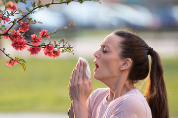 Woman sneezing because of spring pollen allergy