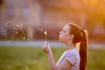 Woman blowing dandelion flower