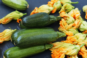 Vegetables and flowers of zucchini, located on a dark background in random order