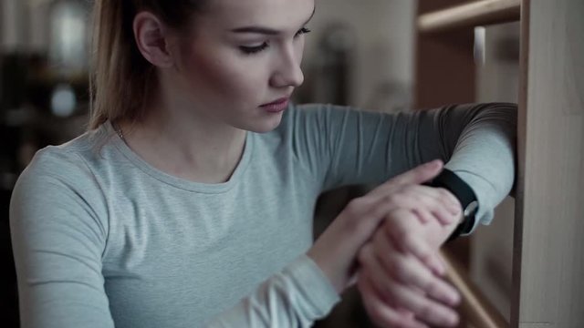 Young girl or woman in a gym, using smartwatch. Slow motion.