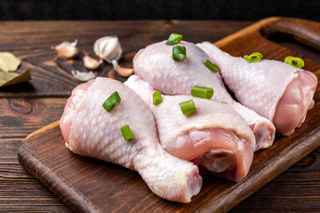 Raw chicken legs on dark wooden background.