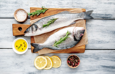 chilled raw fish sea bass and Dorado with ingredients on a cutting board on a wood background