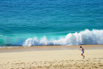 Woman jogging on the beach with a beautiful waves