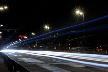 Fototapeta na wymiar long exposure of lights on road at nighttime near illuminated buildings