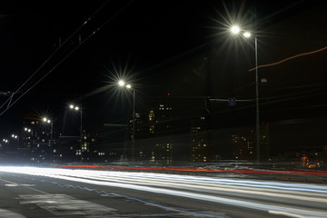 Fototapeta na wymiar long exposure of lights on road at night near illuminated buildings