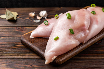 Raw chicken breast or fillets on dark wooden background. 