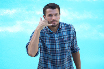 portrait of an adult man shows the hand phone. Background swimming pool.