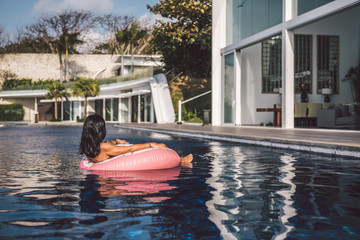portrait of a sexy woman relaxing in a big pool on an inflatable pink donut