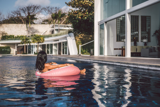 portrait of a sexy woman relaxing in a big pool on an inflatable pink donut