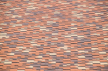Roof from multi-colored bituminous shingles. Patterned bitumen shingles.