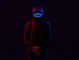 Dangerous hooded man in futuristic 3d glasses with virtual projection over dark background.  in glasses of virtual reality. Augmented reality, science, future technology, robots, people concept.