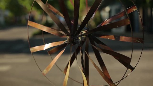 Rustic Metal Pinwheel Spins in the Breeze on the Side of a City Street