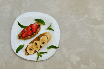 Healthy vegan toasts with pumpkin seed butter, banana and strawberries. Top view, image with copy space
