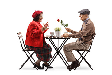 Elderly man sitting at a cafe and giving a red rose to an elderly lady