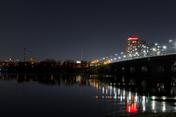Fototapeta na wymiar dark cityscape with illuminated buildings, bridge and river