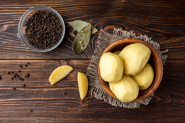 Peeled potato on dark wooden background. 