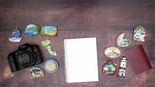 Camera passport and notebook with travel magnets on wooden table - Stop motion 
