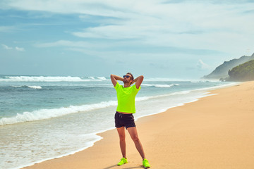 Sportsman stretching on a tropical sandy beach.