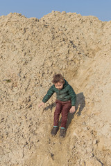 Fototapeta premium A little boy is climbing a sand mountain.