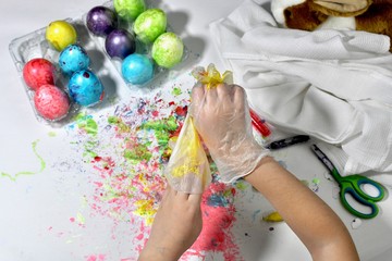Childish hands take off protective gloves after painting Easter eggs.