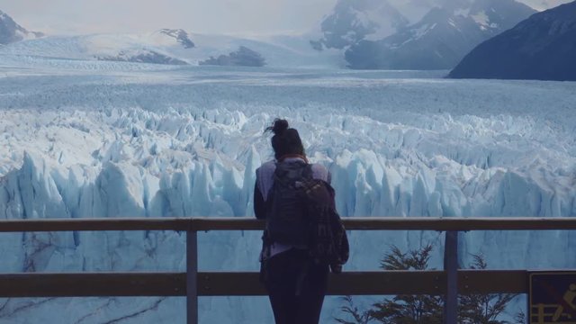 Female tourist contemplating the impressive Glaciar Perito Moreno from a terrace of the National Park Los Glaciares. 4k