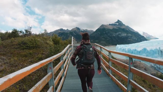 Woman running on the corridor in front of the impressive Glaciar Perito Moreno of the National Park Los Glaciares. 4k
