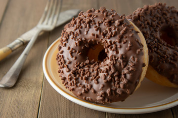 Chocolate donuts breakfast or dessert, wooden table. Close up glazed donuts. Sweet food. Pastry.