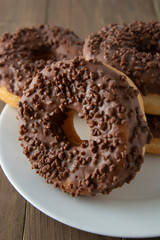 Chocolate donuts breakfast or dessert, wooden table. Close up glazed donuts. Sweet food. Pastry.