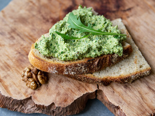 Arugula pesto with walnut. Sandwich with pesto on a wooden plate. Healthy breakfast. vegetarian food. Selective focus, copy space, close up, rustic.