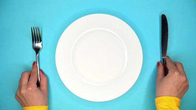 Table setting in restaurant or cafe. Fork and knife. Female hands puts and takes away white plate from blue table