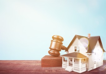 Wooden judge gavel and toy  house on  background