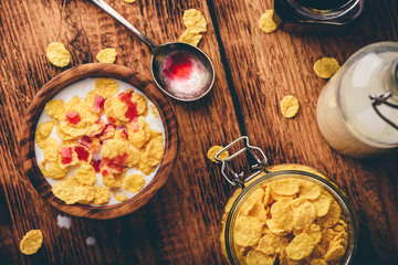 Breakfast with corn flakes, milk and berry syrup