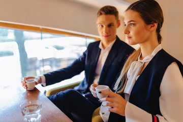 A stylish couple drinks morning coffee at the cafe, young businessmen and freelancers