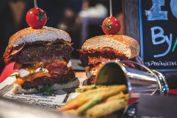 Delicious last-minute gourmet hamburger cut in half with cheddar bacon with small tomatoes accompanied with fries