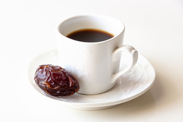 White cup of coffee and one dates white background isolated.