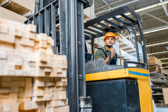 selective focus of indian warehouse worker sitting in forklift machine
