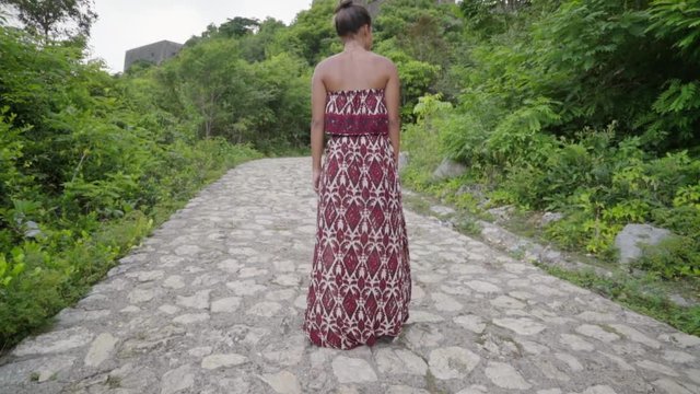 Bare Shouldered Woman with Hair in Bun Walks Uphill toward Ancient Building in Citadel Laferriere, Haiti